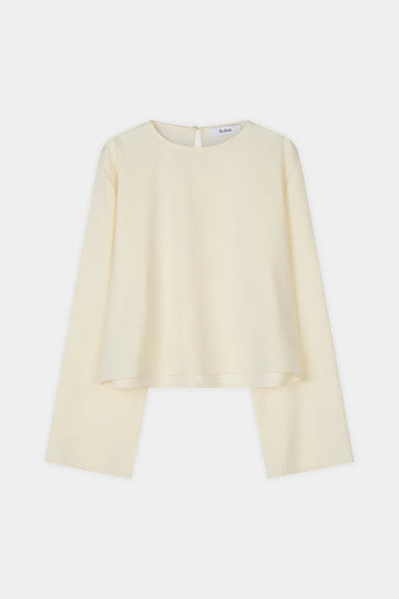 A pale cream long-sleeve blouse with a round neckline and a unique asymmetrical hemline, displayed flat against a light gray background.