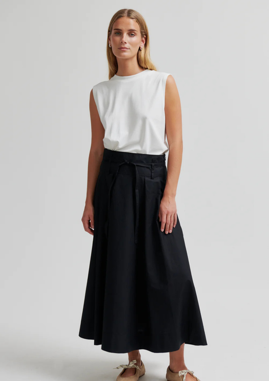 model wearing black skirt and white top