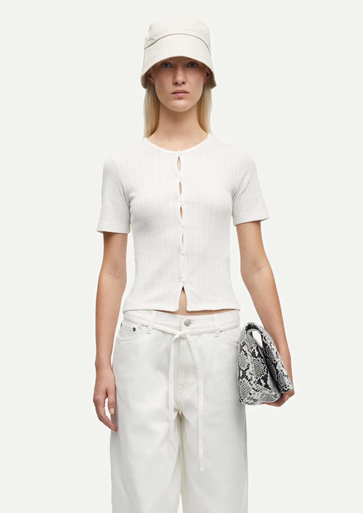 model wearing white cardi and cream jeans on plain background