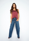 A woman modeling a sleeveless dusty rose top and wide-leg blue jeans against a plain white studio background.