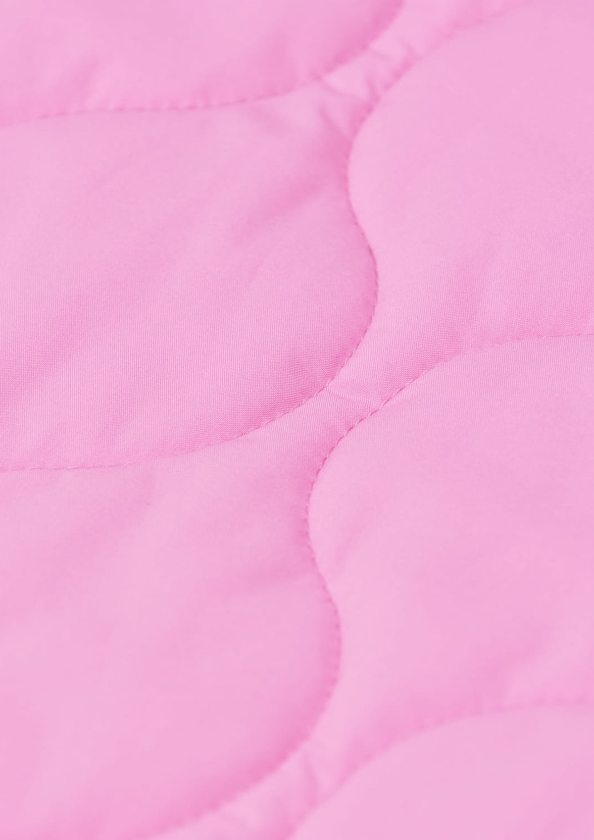 A close-up of a light pink quilted fabric with scalloped stitching.