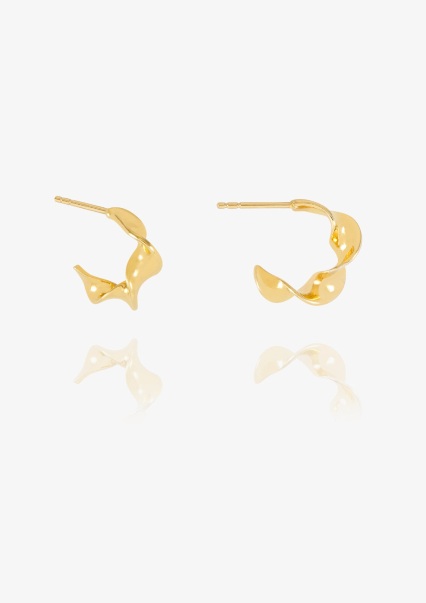 A pair of gold hoop earrings with a twisted, organic abstract design, displayed on a clean white background with a soft reflection below.