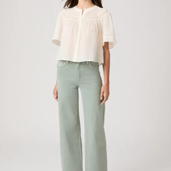 Woman wearing a white blouse and light green pants on a white background