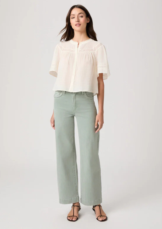 Woman wearing a white blouse and light green pants on a white background