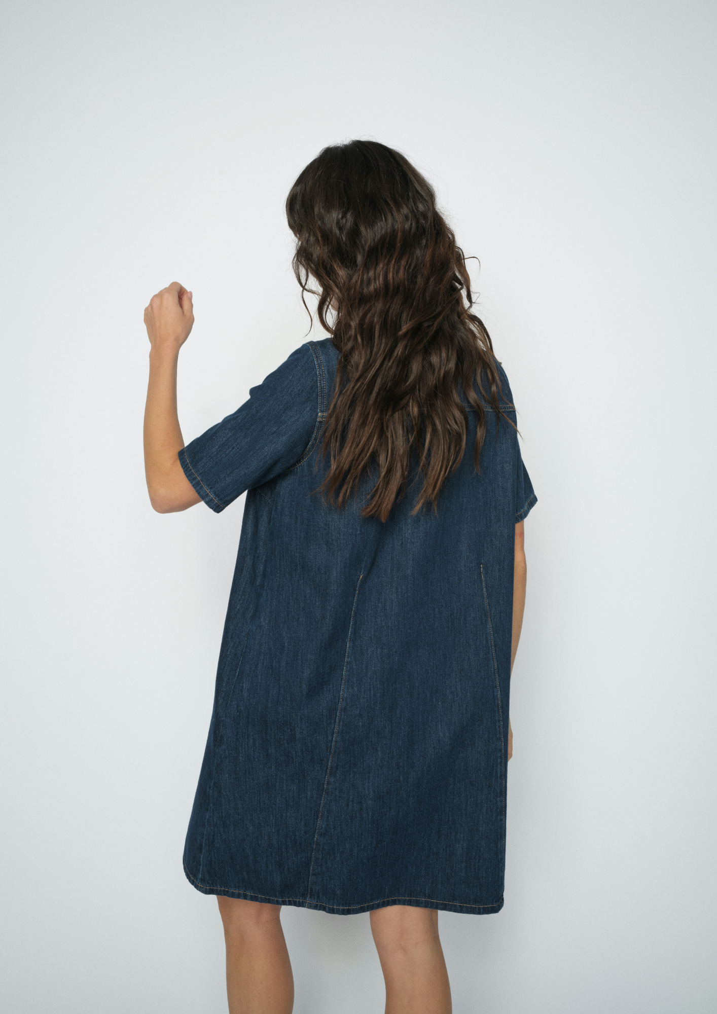 A child wearing a dark blue denim short-sleeve dress, shown from the back against a plain white studio background.