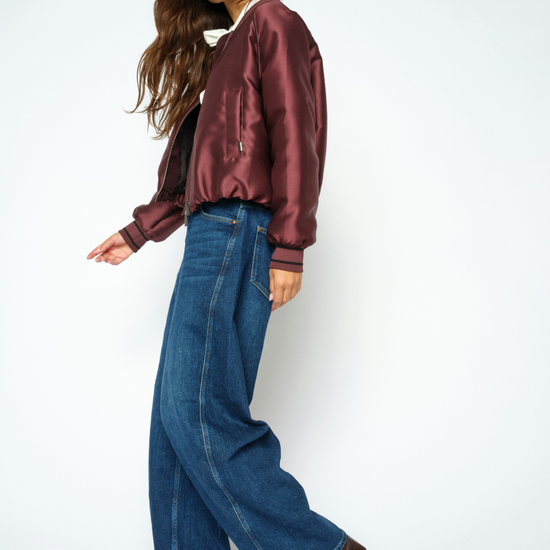 Woman wearing blue jeans and a purple coat, side view