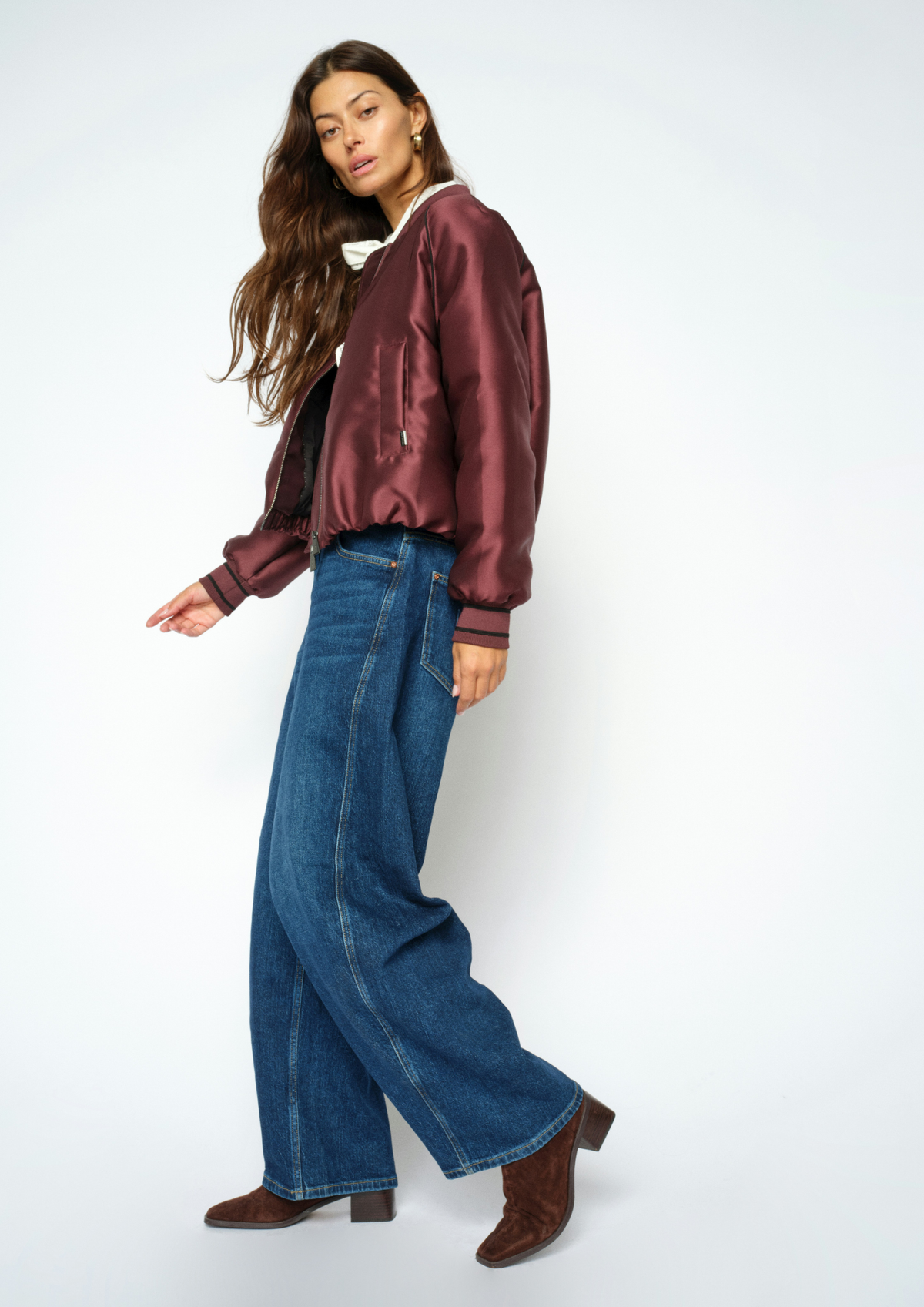 Woman wearing blue jeans and a purple coat, side view