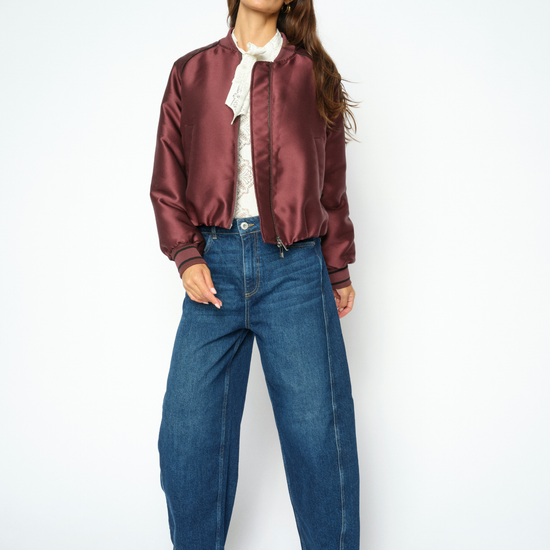Woman wearing blue jeans and a purple coat