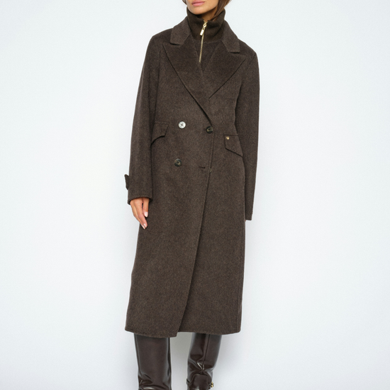A model wearing a dark brown double-breasted wool coat with a high collar, paired with dark brown leather boots, against a light gray studio background.