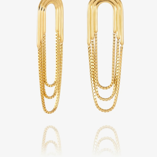 A pair of gold paperclip-shaped drop earrings with layered chain details, displayed on a clean white background with a soft reflection below.