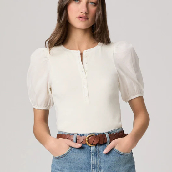 Woman wearing a white blouse and denim skirt on a plain background