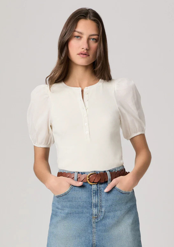 Woman wearing a white blouse and denim skirt on a plain background