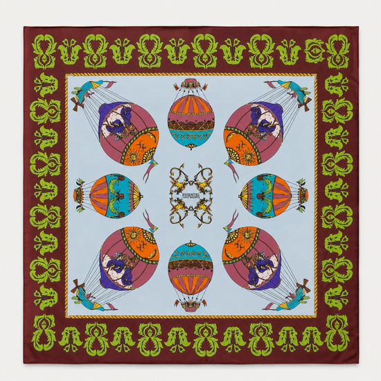 A square silk scarf featuring a colorful hot air balloon pattern on a light blue background, surrounded by a brown border with green and gold decorative motifs.