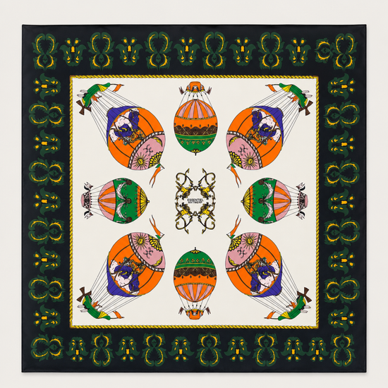 A square scarf featuring a symmetrical, colorful hot air balloon pattern on an off-white center field, surrounded by a black border with green and gold decorative motifs.
