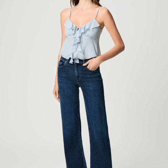 Woman wearing a light blue top and dark blue jeans on a white background