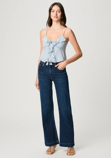 Woman wearing a light blue top and dark blue jeans on a white background