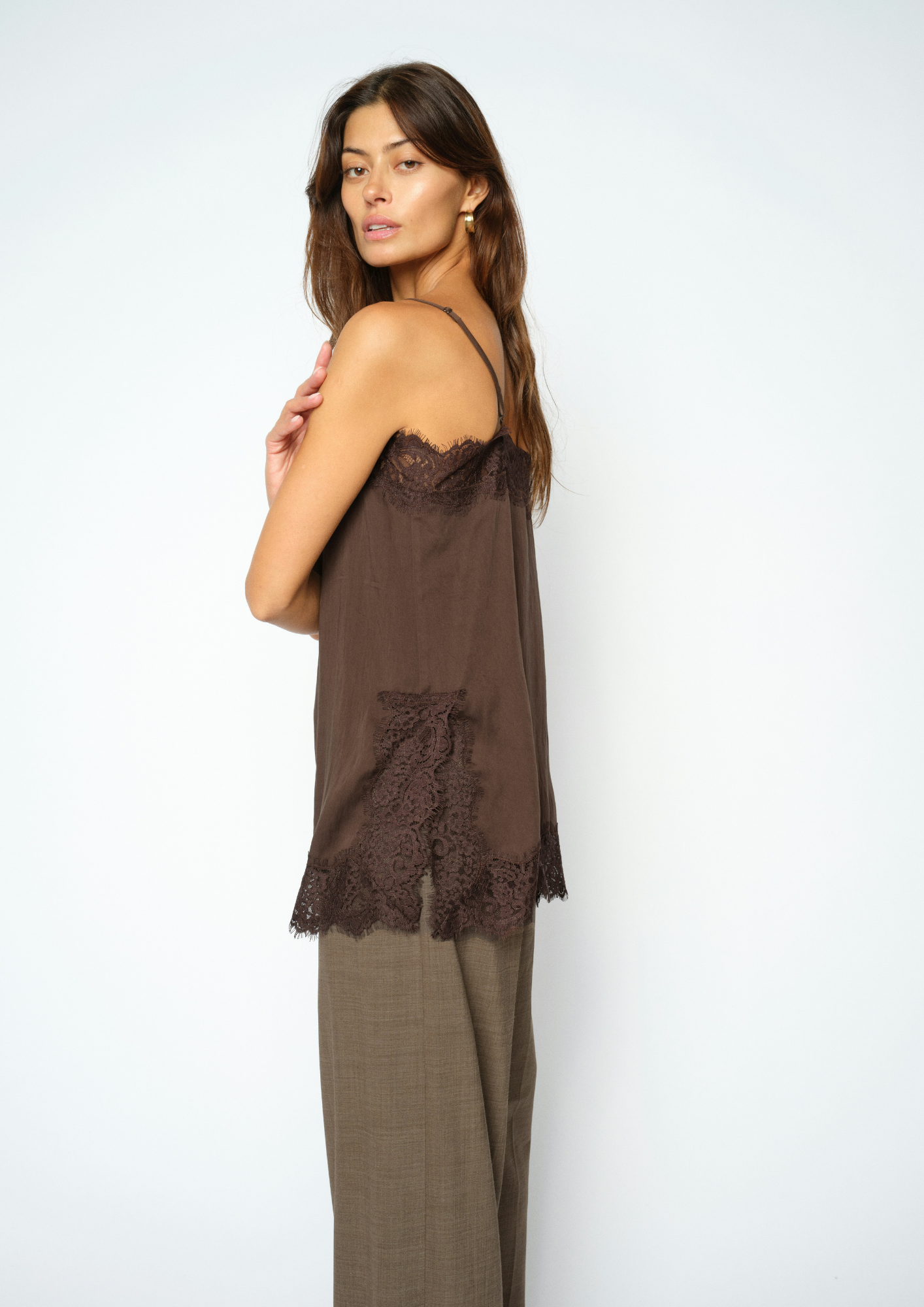 woman wearing brown lace cami and check trousers side view