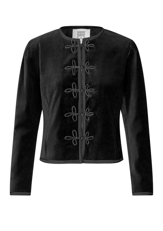 model wearing black leather trousers and a black velvet nepoleon style jacket with a plain background