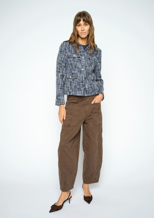 A woman modeling a blue and white textured tweed jacket paired with brown wide-leg cropped pants and dark brown pointed-toe heels, set against a plain light gray studio background.