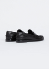 A pair of black leather penny loafers shown from the rear three-quarter view on a clean white studio background.