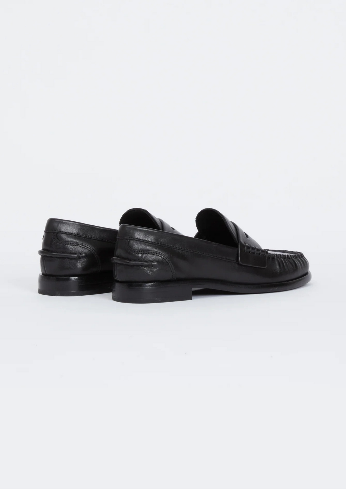 A pair of black leather penny loafers shown from the rear three-quarter view on a clean white studio background.