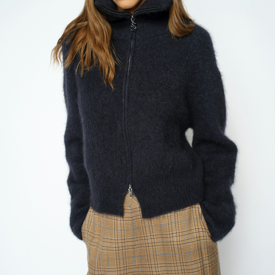 Woman wearing blue zip sweater and brown trousers 