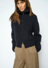 Woman wearing blue zip sweater and brown trousers 