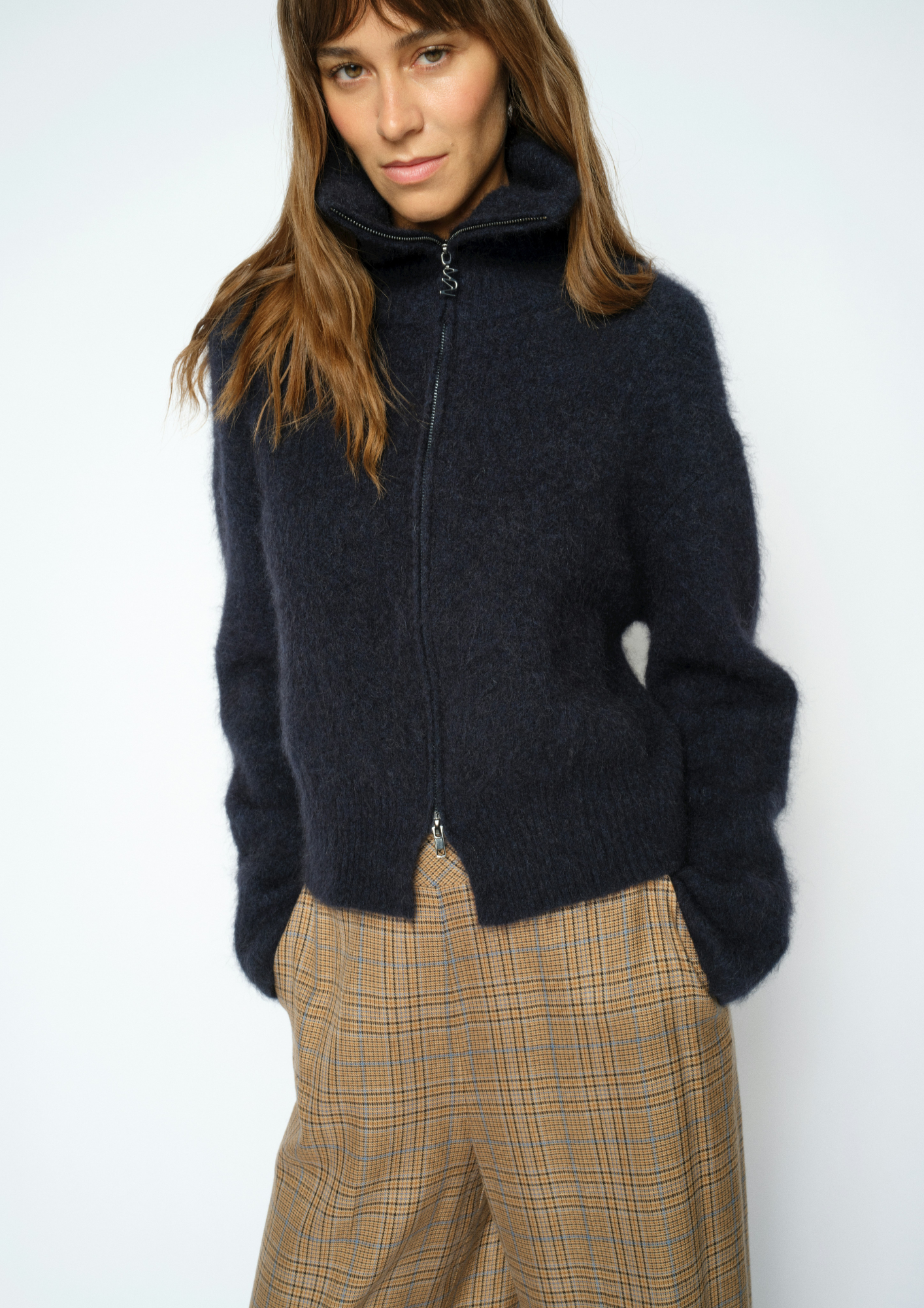 Woman wearing blue zip sweater and brown trousers 