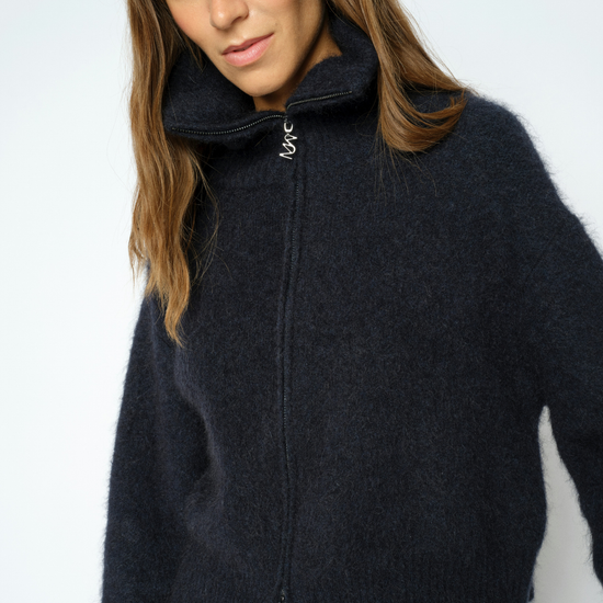 Woman wearing blue zip sweater and brown trousers close up 