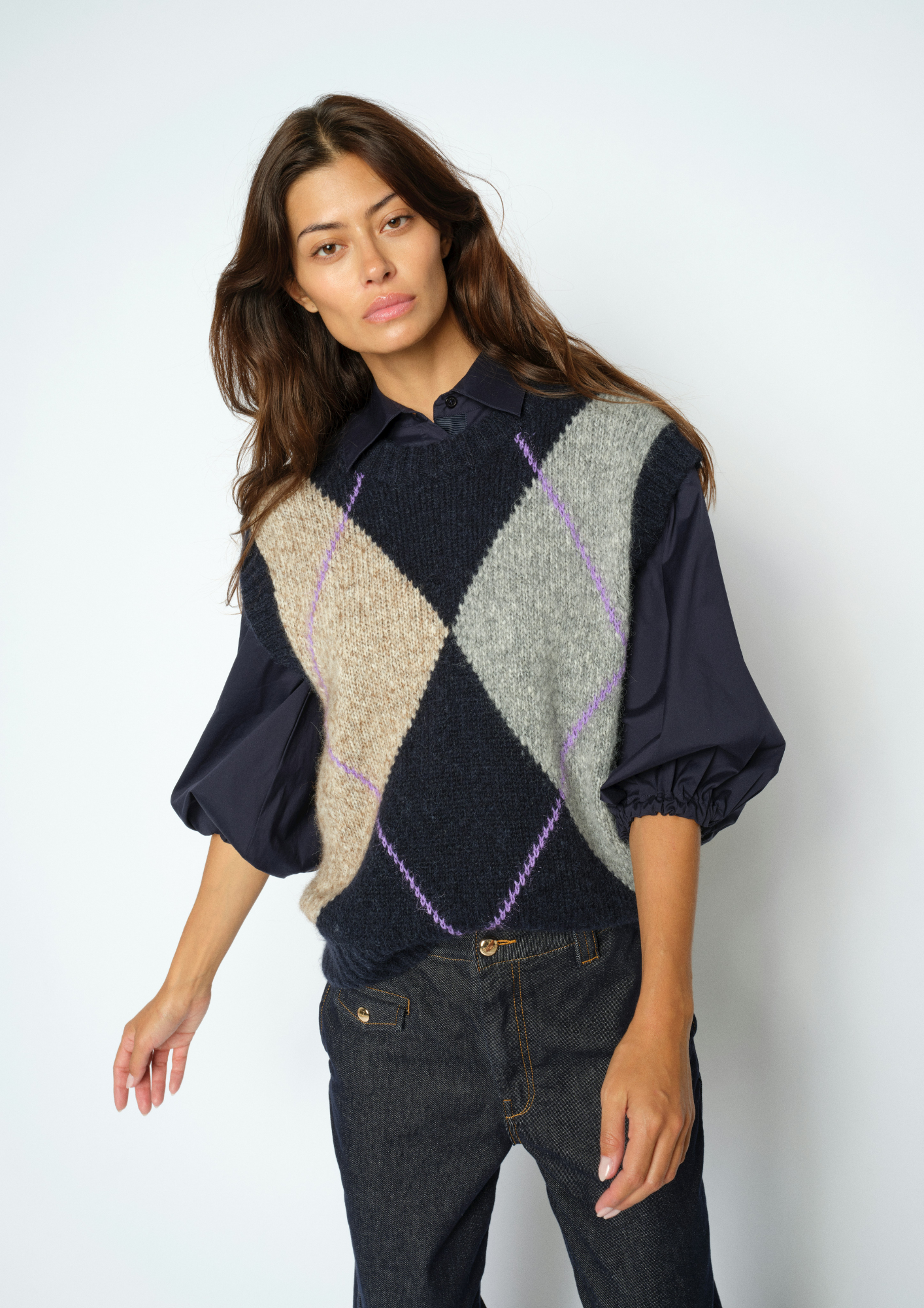 Woman wearing Blue, grey and beige Argyle vest with a blouse underneath