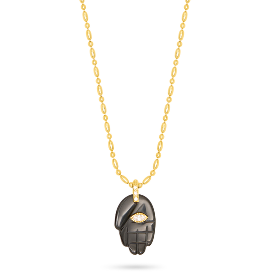black hand pendant on a gold chain, with a gemstone in the centre, as a flat lay image on a plain white background 