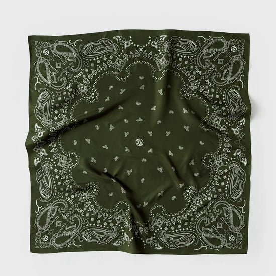 A green bandana with a white paisley and floral pattern, laid flat on a light gray background.