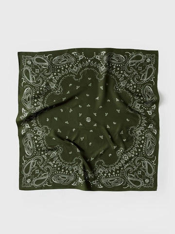 A green bandana with a white paisley and floral pattern, laid flat on a light gray background.