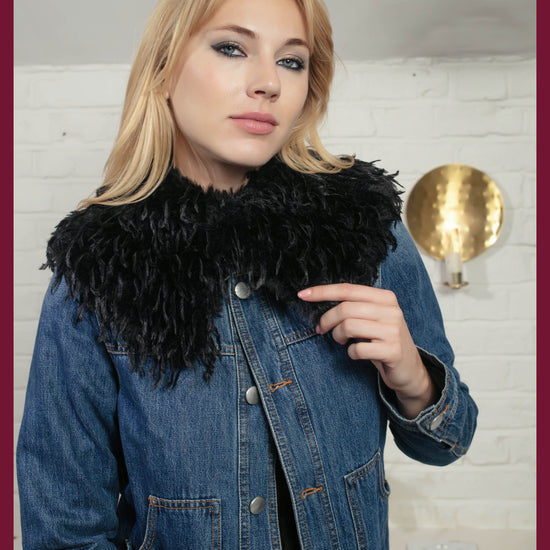 Woman wearing a black fur collar over a denim jacket in an indoor setting.