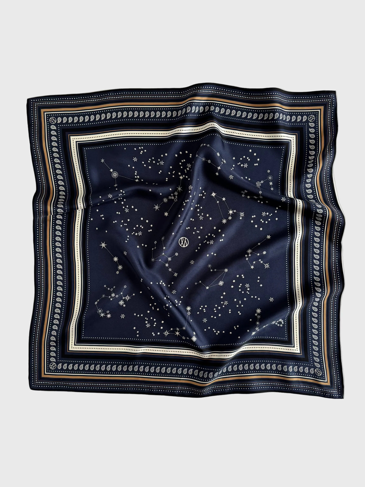 A square navy blue silk scarf featuring a celestial print of stars and constellations, framed by a decorative border with cream, gold, and navy stripes, laid flat on a light gray background.