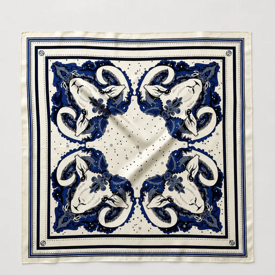 A square silk scarf with a classic blue and white baroque-style floral pattern, laid flat against a light gray background.