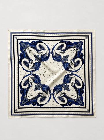 A square silk scarf with a classic blue and white baroque-style floral pattern, laid flat against a light gray background.