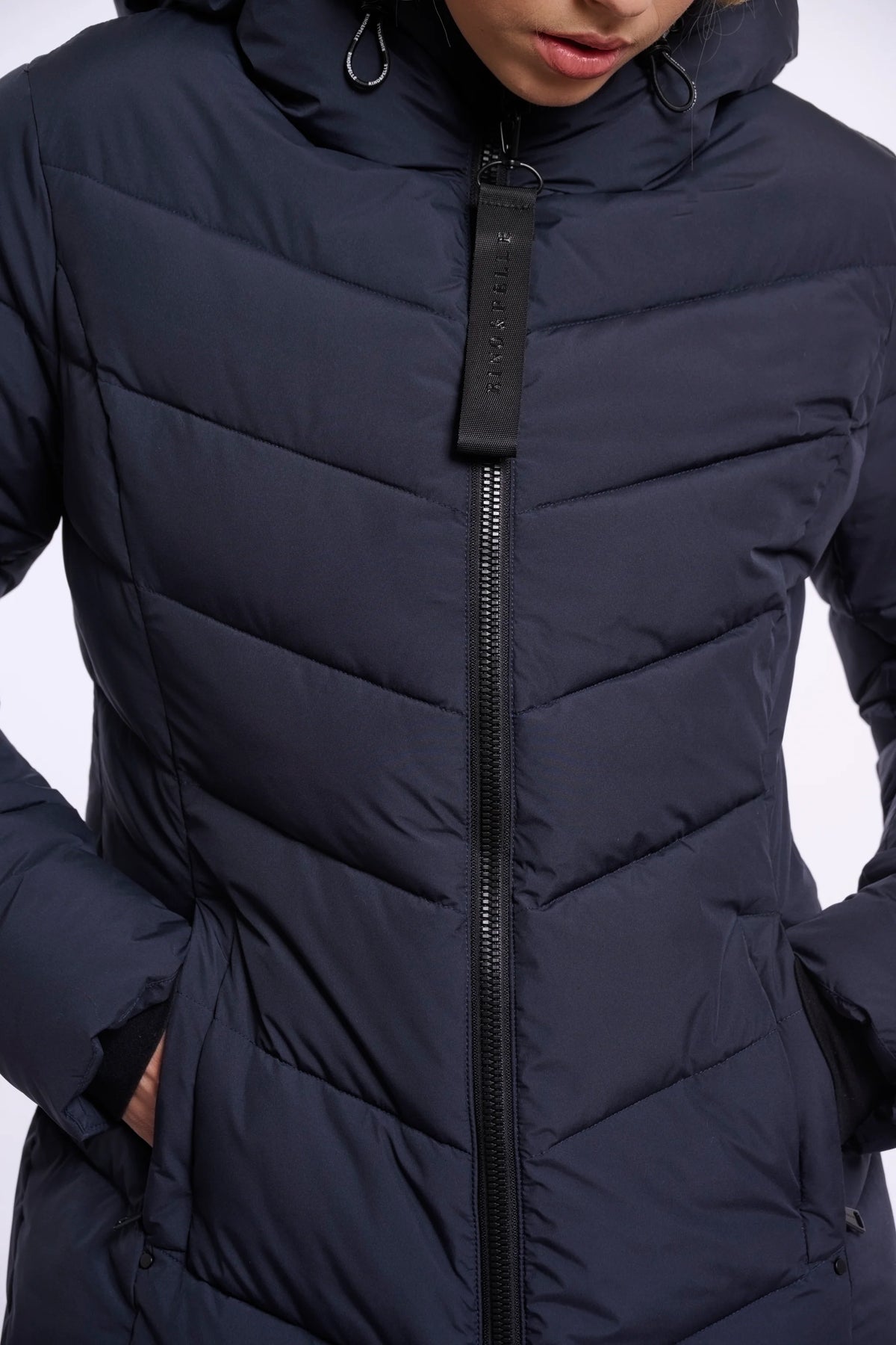 Close-up of a person wearing a black puffer jacket with a hood on a white background