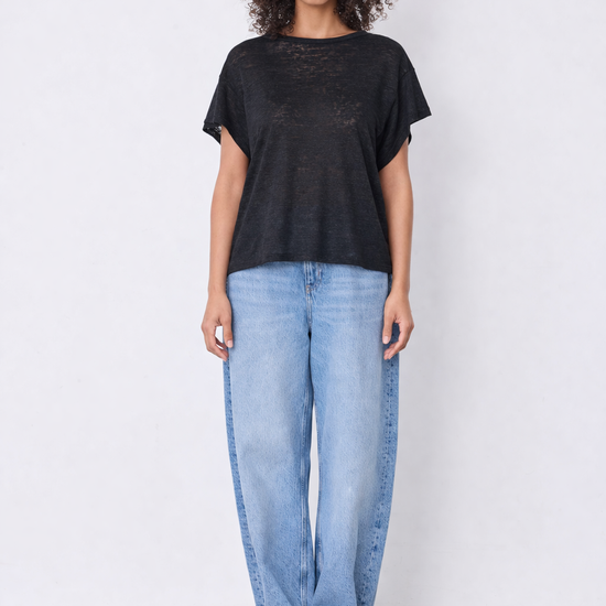 Model wearing black top and blue jeans on plain background 