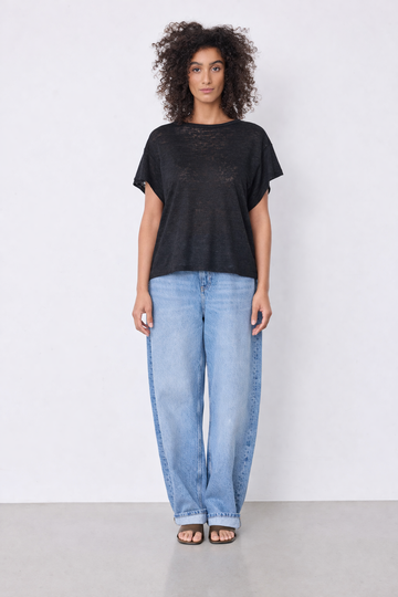 Model wearing black top and blue jeans on plain background 