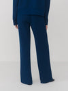 Rear view of a person wearing navy blue wide-leg trousers with a matching navy top, photographed against a light gray studio background.