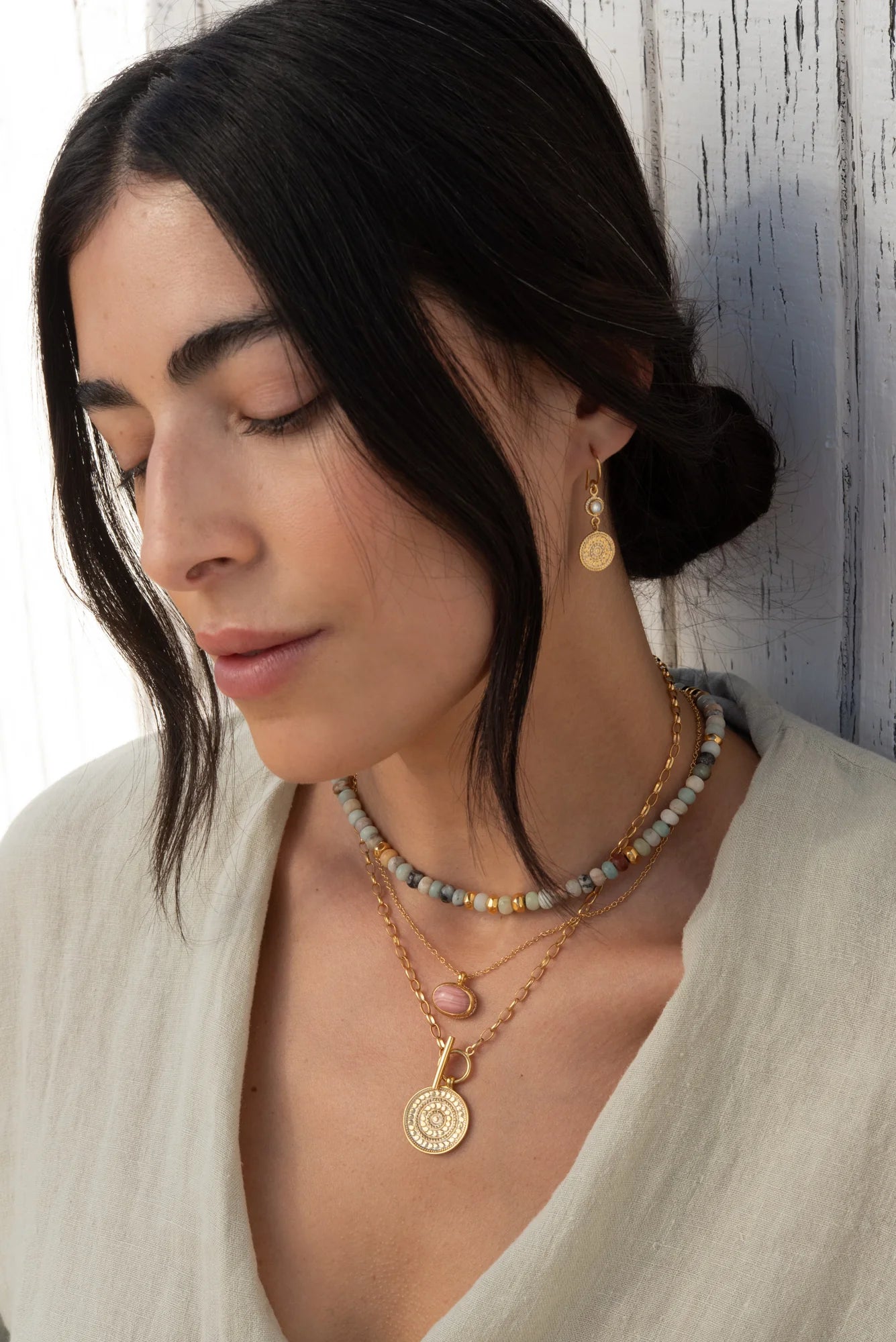 Gold necklace with toggle fastening and coin shaped pendant featuring dot work