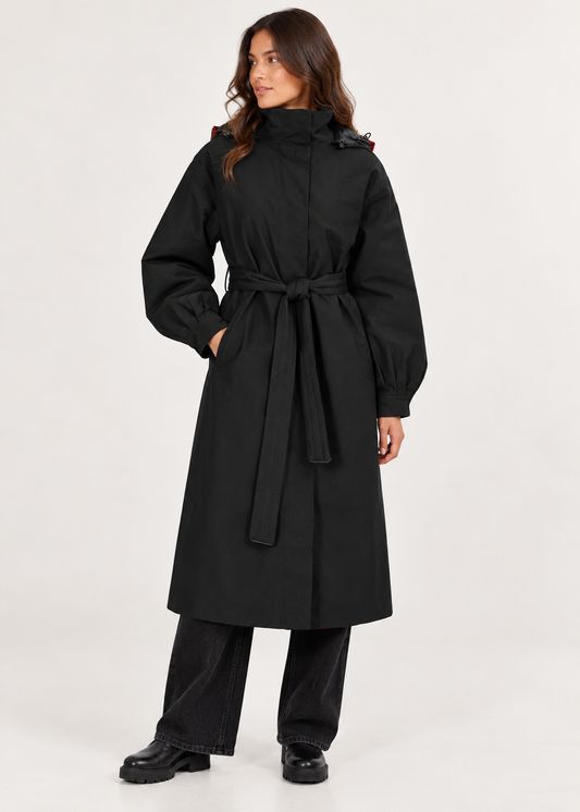 model shown wearing a black long waterproof coat with black jeans and boots on a plain white background