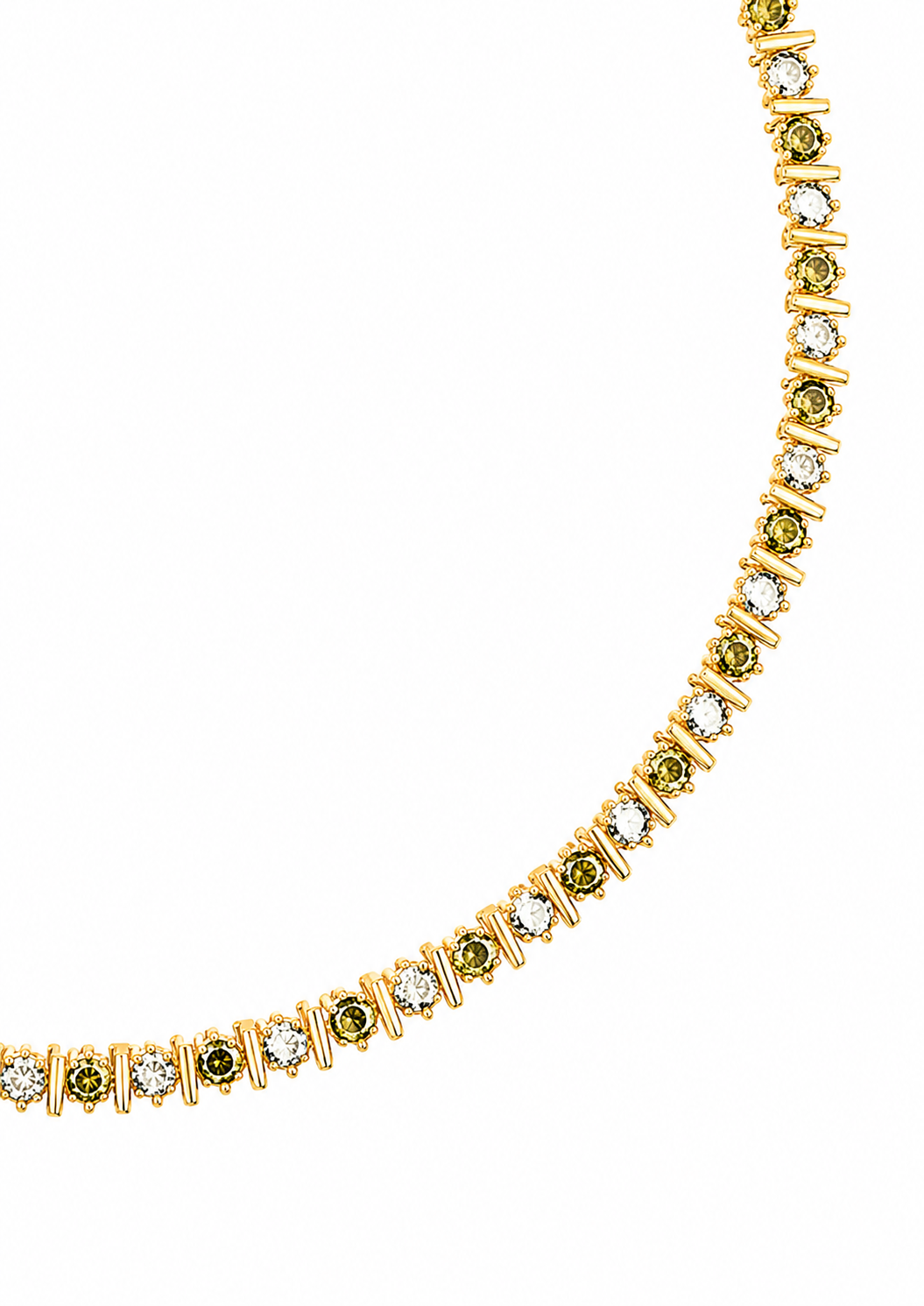 A gold tennis necklace featuring small green gemstones and clear stones, displayed on a clean white background. A gold tag is attached near the clasp.