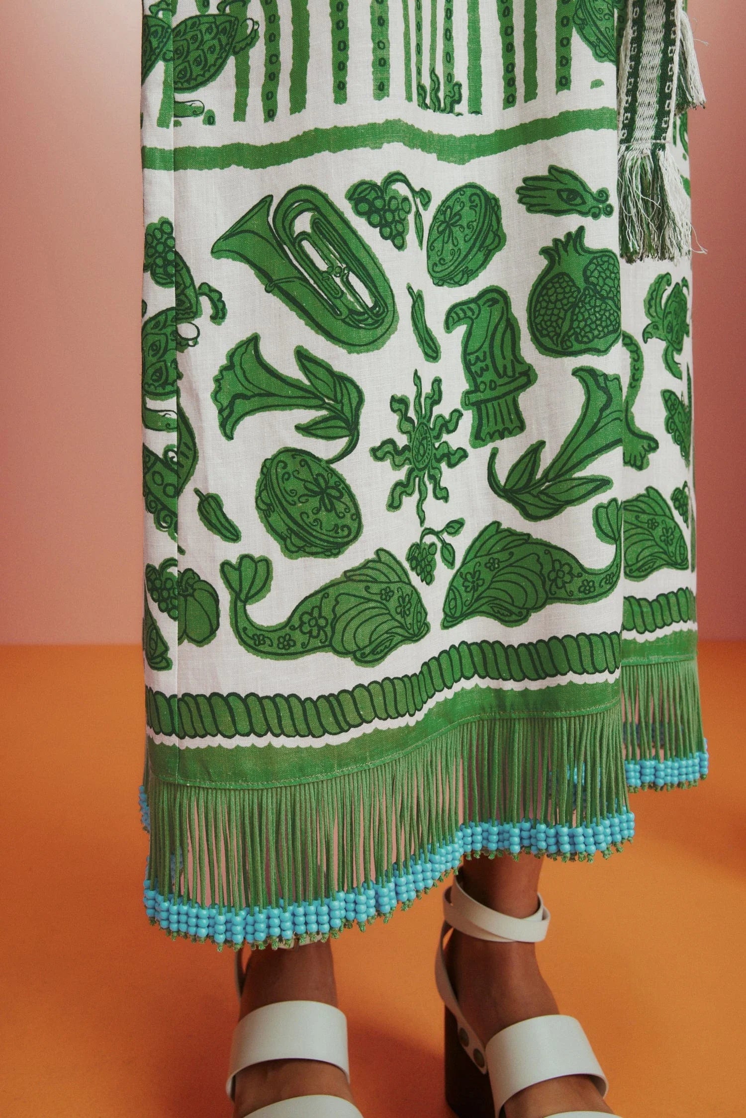 Sleeveless green printed sun dress with fringe detail on the hem close up