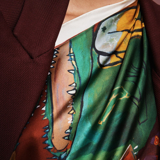 Colorful patchwork scarf with floral and abstract patterns by Alemais on a white background being worn by a woman close up