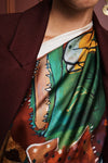 Colorful patchwork scarf with floral and abstract patterns by Alemais on a white background being worn by a woman close up