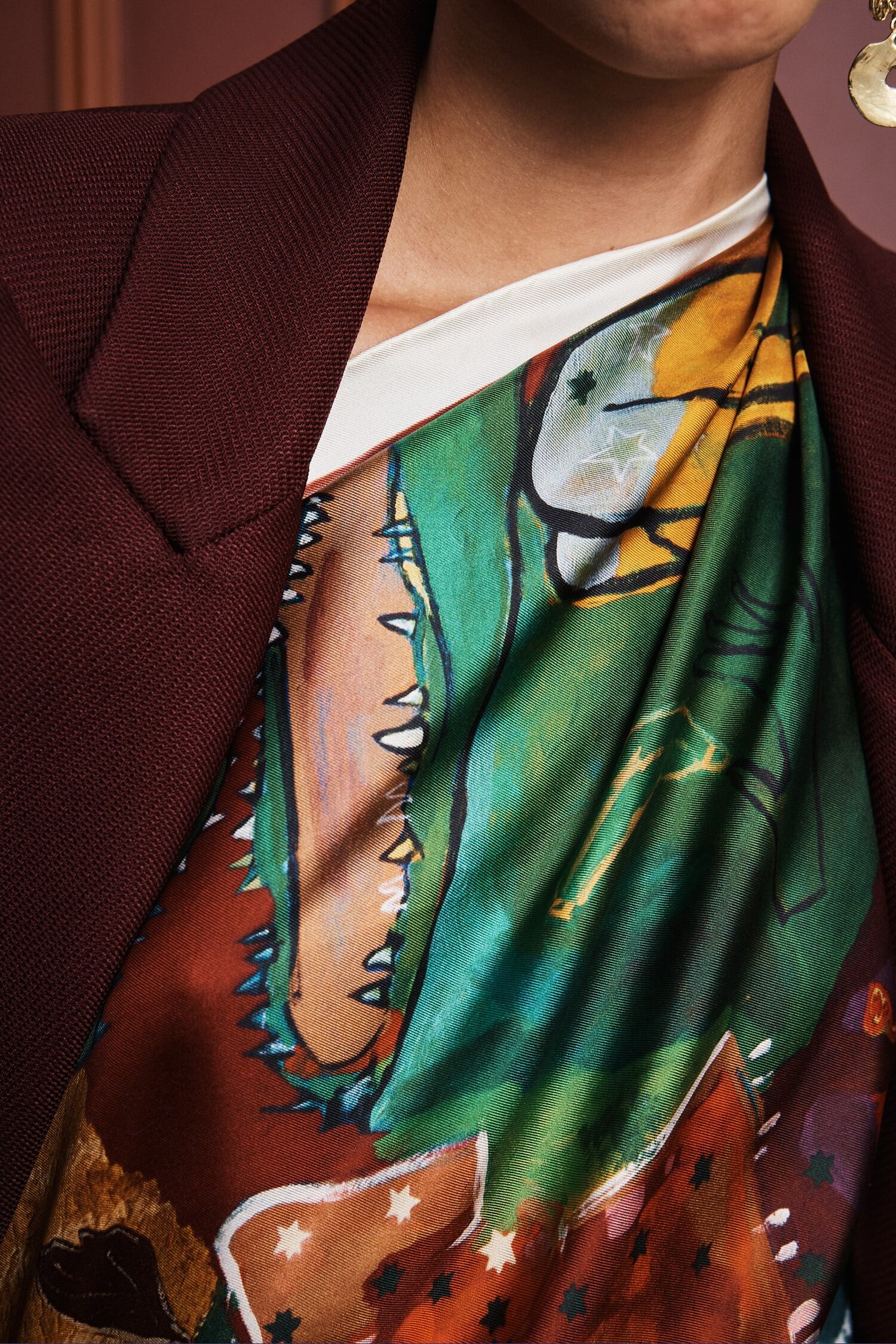 Colorful patchwork scarf with floral and abstract patterns by Alemais on a white background being worn by a woman close up