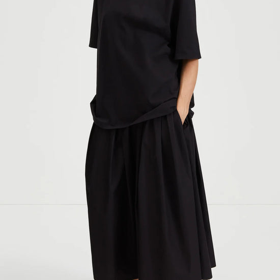 Person wearing a black outfit with a plain background