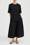 Person wearing a black outfit with a top and skirt on a white background